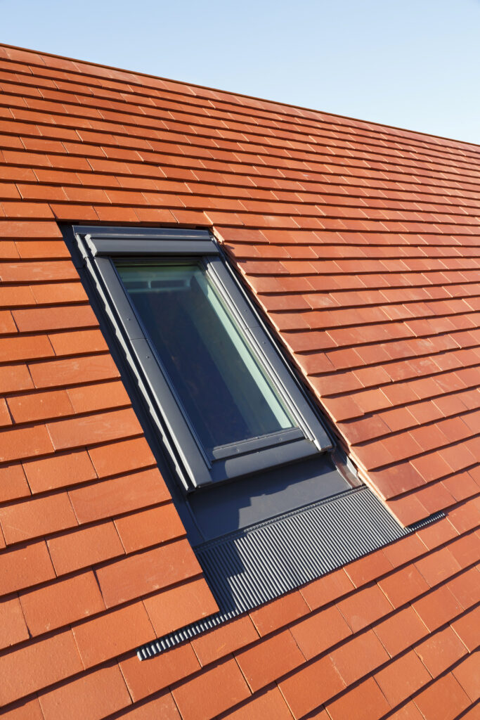 Velux dakraam in een traditioneel pannendak met klassieke kleipannen, dat zorgt voor veel lichtinval en stijl.